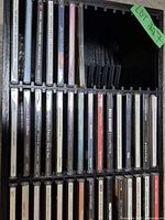 First photo showing one row of assorted CDs in the black plastic CD holder rack. CD titles and artists visible include Willie Nelson and others.