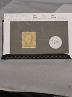Front of the 1932 Canadian 4 cent ochre George V medallion stamp mounted on black card with white sticker labeled 326 and notes about the condition.