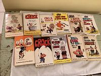 Top view of all 11 Crock comic books arranged in two rows on a light green wooden surface, showing full cover art and titles.