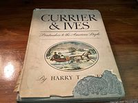 Front cover of the book with title, author, and oval colored illustration of a horse-drawn sleigh in a snowy landscape. Dust jacket shows torn and missing pieces at lower corners and edges.