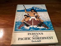 Front cover of the softcover book showing the title and illustrated artwork of Indigenous men in a canoe.