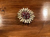 Front view of the vintage gold-tone Lisner brooch showing flower design with red rhinestones in the center.