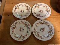 Four Minton Spring Flowers bread plates arranged on a wooden surface showing the front floral design.