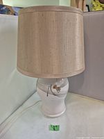 Full view of the pottery lamp with beige fabric shade.