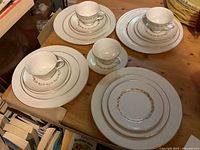Four place settings of Royal Doulton Fairfax dinnerware arranged on a wooden table, each setting including a teacup, saucer, dinner plate, salad plate, and bread plate.