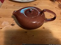 Top side view of brown ceramic teapot showing spout, handle and lid