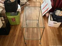 Top-down view of the vintage brass tea trolley showing the top glass shelf and brass frame with handle.