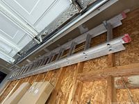 Full view of the 14 foot aluminum extension ladder resting horizontally against a wall.