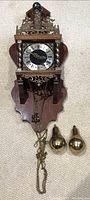 Front view of antique Dutch Zaanse Warmink wall clock showing clock face, brass weights, and wooden backplate.
