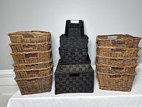 Stack of 6 natural wicker baskets on the left and 6 black synthetic woven baskets in the center, rectangular shapes with handles.