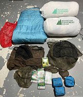 Photo showing blue Sierra Design sleeping bag and two white Mountain Equipment Co-op storage bags, several brown mesh insect nets and small blue pouches.