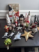 Overall lot showing wooden 'Let It Snow' sign, various snowman and Santa figurines, star ornaments, ice skates, and glass ornament.