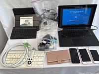 Front view showing all items including Windows laptop, smartphones, keyboards, cords, and accessories