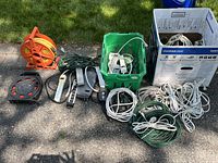 Overview showing two cord reels, green crate of power strips, cardboard box of cables, loose extension cords and power strips