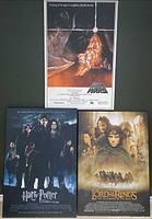 Three laminated wood movie posters: Star Wars, Harry Potter and the Goblet of Fire, Lord of the Rings: The Fellowship of the Ring, photographed hanging on a wall.