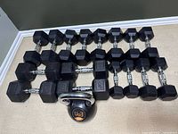 Overview of all eight dumbbell pairs and one kettlebell arranged on carpet