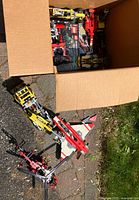 Overview of cardboard box containing multiple partially assembled LEGO Technic and Racers models
