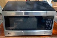 Front view of LG microwave oven showing stainless steel exterior and dark glass door.
