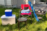 Full lot view with coolers, red folding chair with towels, small glass-top table, beach umbrella bag, and weight bags.