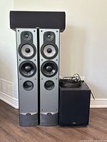 Front view of two tower speakers and subwoofer with cables