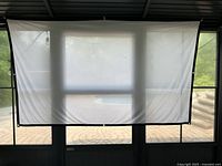 Projection screen hung indoors showing fabric texture, light translucent material with black border