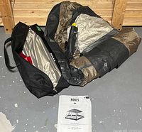 Overview photo showing folded screenhouse tent fabric, black carrying bag, and the instruction manual on the floor.
