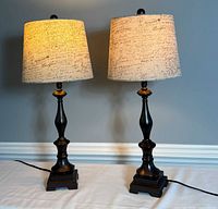 Pair of matching Paris-themed table lamps with warm light on, showing full view of both lamps side by side.