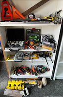 Three-shelf cabinet and floor displaying full assortment of tools including levels, clamps, pliers, screwdrivers, mallets and saw