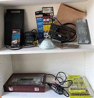 Multiple rotary tools and accessories on shelves including a Dremel MultiPro rotary tool, electric sander, sanding sheets, respirator mask and a wooden box with bits.