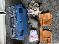 Contents of lot laid out including toolbox, two pairs of protective glasses, two pairs of gloves, ear protection earmuffs, suede tool belt and disposable ear plugs in bag.