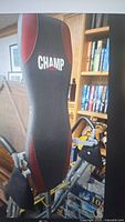 Full view of the Champ black and red inversion table showing padded backrest, metal frame, and padded ankle supports.