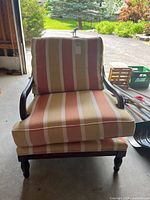 Front view of the wood framed armchair with striped upholstery in beige, brown, and muted red stripes.