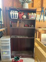 Wooden bookshelf with five shelves, dark finish, showing dust and dirt on shelves. Top shelves hold miscellaneous objects that are excluded from sale.