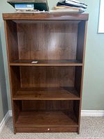 Front view of the wooden bookshelf showing three shelves and a bottom section with keyhole.