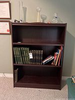 Front view of the three-shelf wooden bookcase showing scuff on top and empty shelves.
