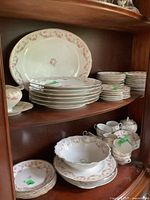 Photo of stacked dinner plates, platter, bread and butter plates, saucers, serving bowl and other china with pink floral pattern