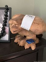 Front angle view of the carved wooden eagle sculpture showing the detailed face, beak, and talons along with the auction label on top.