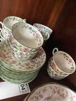 Stack of cups and saucers showing floral pattern and green trim, arranged together