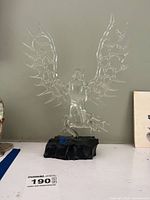 Full view of the clear glass owl sculpture on black base from the front, showing detailed wings and body shape.