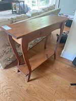 Front angle showing the pine hall table with curved legs and lower shelf, positioned in a living room area.