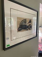 Full front view of framed Inuit art print showing black wood frame, white mat, and stylized raven image