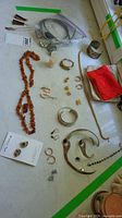 Overview of amber necklace, brooch, porcelain earrings on card, sterling silver bracelets, chains and various earrings