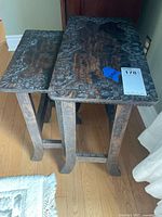 Two nesting tables stacked, showing wood grain and floral carvings on top.