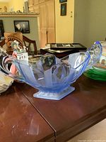 Blue uranium glass bowl showing full side profile with curved handles and geometric faceting.