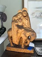 Full view of the wooden Holy Family carving, showing Mary holding baby Jesus and Joseph beside them, mounted on a carved base.