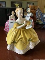 Front view of the Royal Doulton figurine in yellow dress holding a fan.