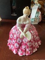 Front side view of Royal Doulton figurine Victoria HN 2471 showing pink floral dress and fan.