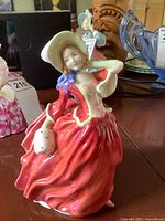 Front view showing detailed facial features, red dress, white hat, and jug held in hand.