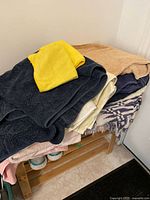 Stack of assorted bath towels and a throw blanket on wooden shelf