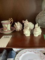 Overall view showing four white ceramic bunny salt and pepper shakers in two sizes and the porcelain demi-tasse cup and saucer.